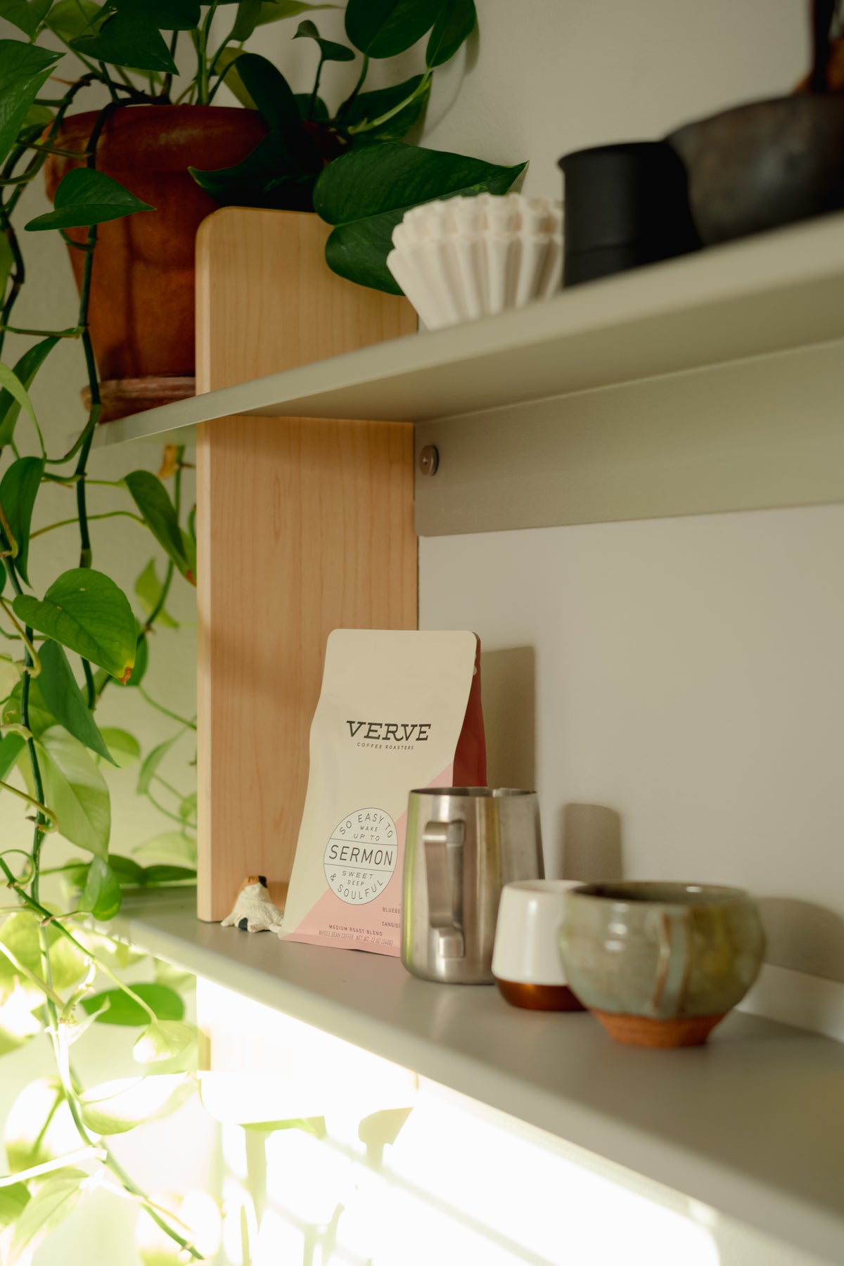 A close-up of the wood-and-metal coffee shelving with mugs and a bag of coffee